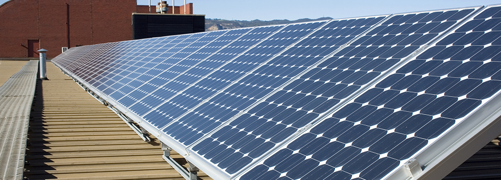 large solar system on commercial rooftop building, clear sky in background
