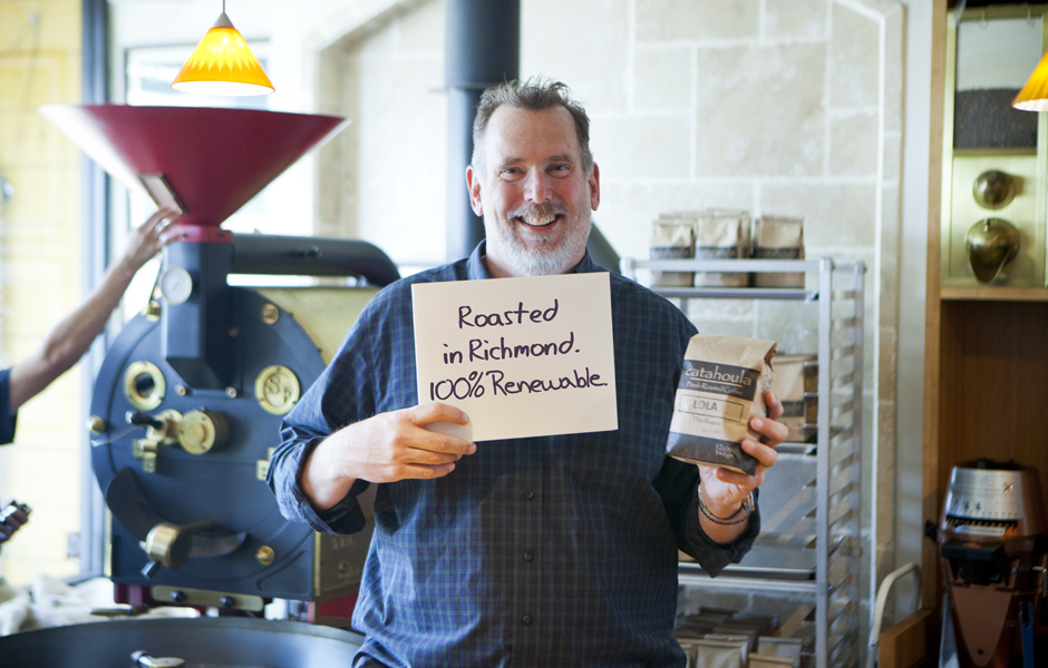 business owner man, holds coffee package and sign, says roasted in Richmond 100% renewable, commercial grade coffee mixer
