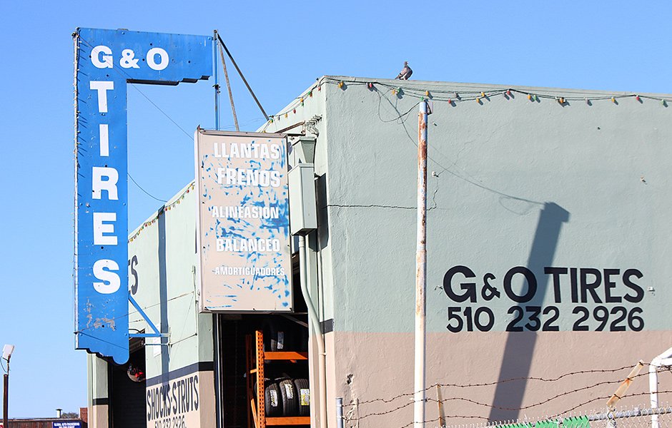 side profile of G&O tires, commercial warehouse building, overhead sign says G&O tires, clear sky,