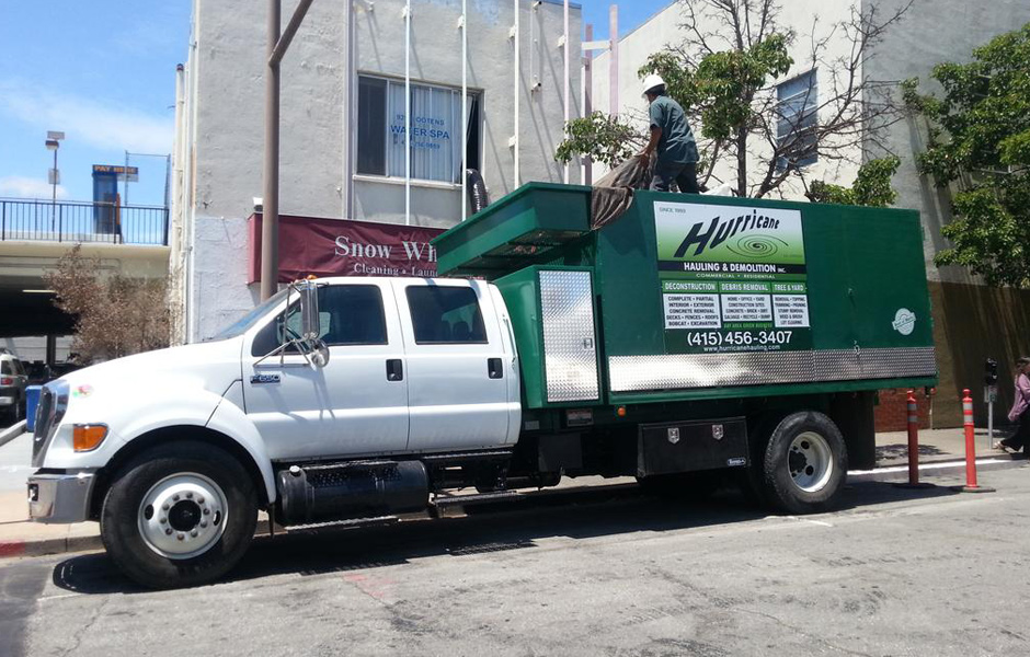 commercial hauling truck, decal says Hurricane Hauling and Demolition, on street of industrial area