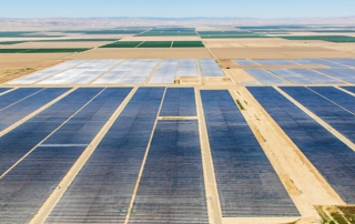 aerial view of massive large scale solar project in desert, agricultural flat land, mountains in distance