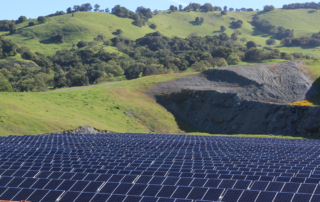 very large commercial size solar project, Cooley rock quarry above, grassy hills, trees, clear sky