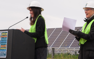 MCE Chief Executive Officer, Dawn Weisz speaks at podium, Board Chair Kate Sears claps, MCE Solar One in background