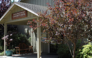 front entrance of two story building, overhead sign says Tamalpais Valley Community Center, two japanese maple trees, bushes