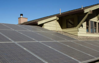 second story close up view of residential home, rooftop solar system, attic window, chimney, clear sky, trees