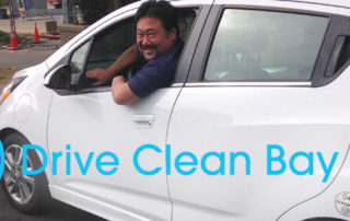MCE Account Manager, Ben Choi, sits in driver seat of electric vehicle, looks back, smiles, logo says Drive Clean Bay Area