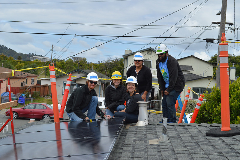 MCE staff member, four GRID Alternatives staff members, smile on top of roof while installing solar system