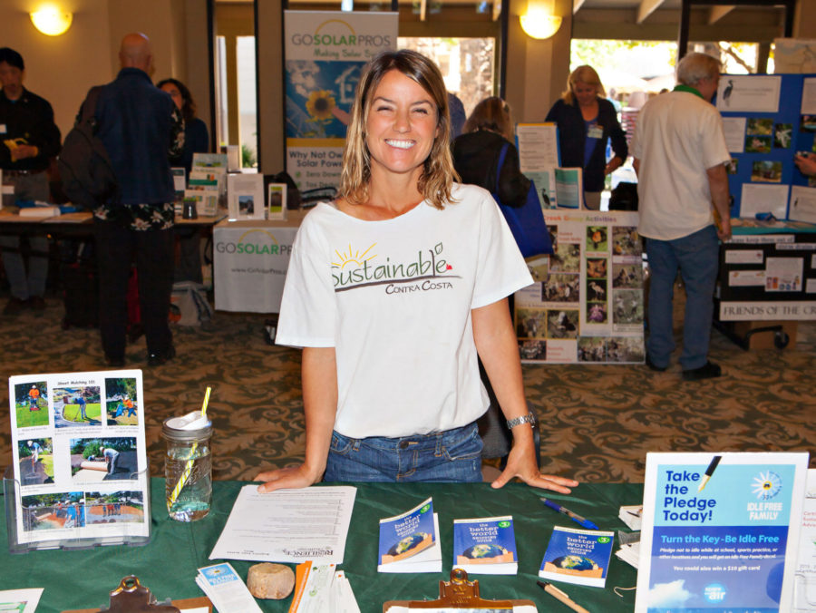 Young Woman Smiling behind table representing sustainable contra costa at a fair